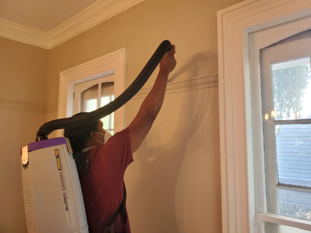 Dust Buster’s employee vacuuming molding ledges during residential cleaning in New Jersey