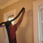 Dust Buster’s employee vacuuming molding ledges during residential cleaning in New Jersey
