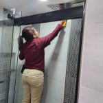 Dust Buster’s employee cleaning shower tiles using a step stool during residential bathroom cleaning in NJ