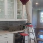 Dust Buster’s employee cleaning on top of kitchen cabinets during a detailed residential cleaning in NJ