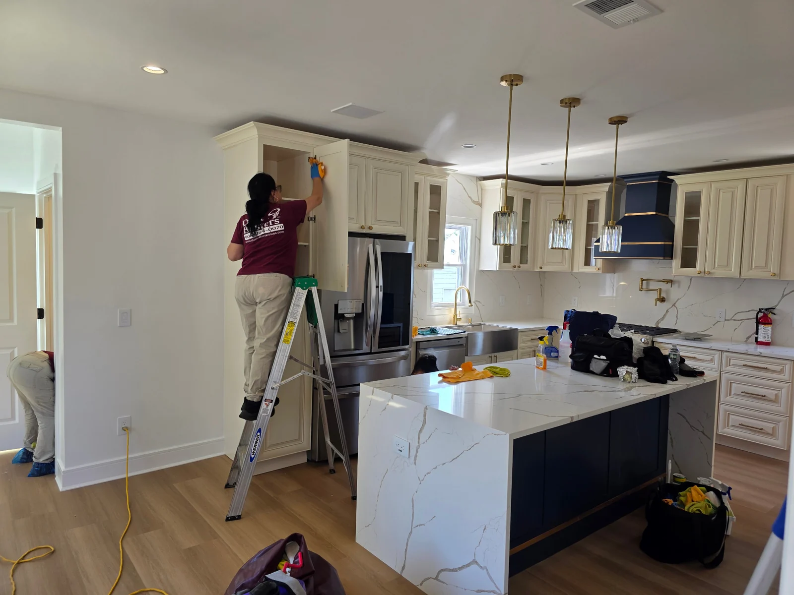 Worker wiping the inside of a kitchen cabinet.