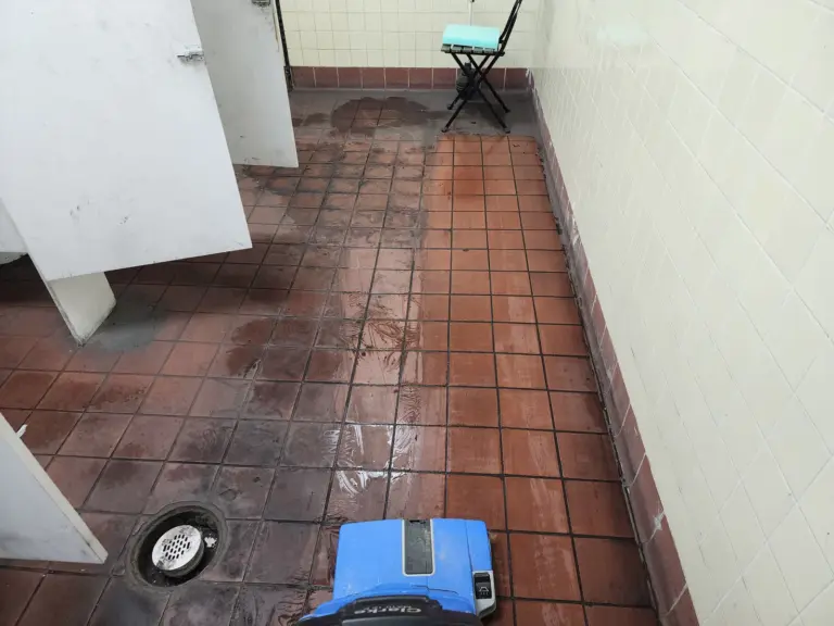 Floor-cleaning machine on a wet red-tile floor during cleaning.